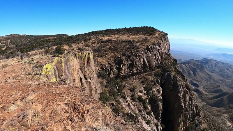 Panoramic view of the South Rim Trail in Big Bend National Park, showcasing rugged cliffs and vast desert landscapes under a clear blue sky.