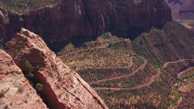 Aerial view of winding switchback roads amidst towering red cliffs in Zion National Park, Utah