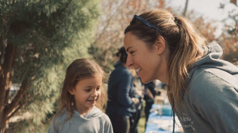 Smiling woman talking to a young girl at an outdoor community gathering